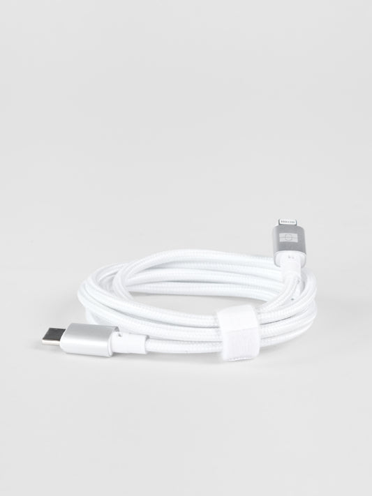 A neatly coiled white braided Schlüssel USB-C to Lightning cable featuring premium silver aluminum connector housings, fastened with a white hook-and-loop strap on a light gray background